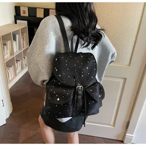 Back view of women's black backpack with white star pattern in a library setting.