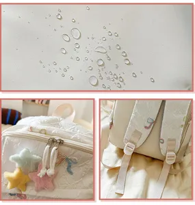 Primer plano de tela impermeable y colgantes de estrellas en una mochila blanca para niñas.