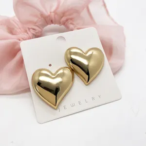 Close-up of bold heart-shaped gold earrings on a display card
