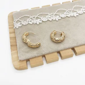 Detailed macro view of gold geometric hollow hoop earrings on velvet display stand