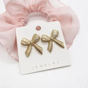 Detailed view of vintage gold textured bow-tie stud earrings on white jewelry card
