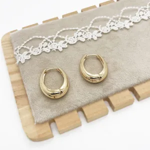 Detail view of chunky gold teardrop hoop earrings on a velvet display pad