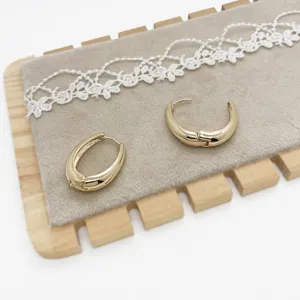 Detail of minimalist gold chunky hoop earrings with polished finish on display board.