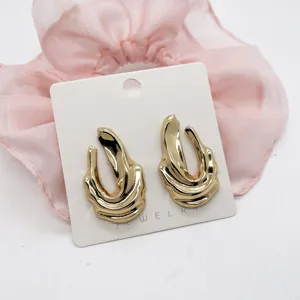 Macro detail of chunky irregular wavy gold earrings presented on a display card
