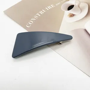 Close-up of a minimalist geometric dark blue resin hair clip on a styled background.