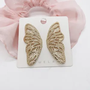 Close-up of gold butterfly wing earrings with hammered texture on a white card
