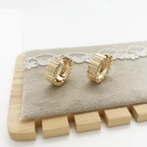 Detailed macro view of gold chunky hoop earrings featuring a geometric pleated design