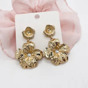 Detailed view of oversized gold floral earrings with elegant white pearl accents