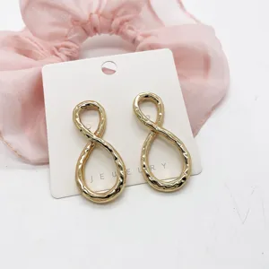 Detailed view of gold geometric infinity earrings with hammered texture on a card.