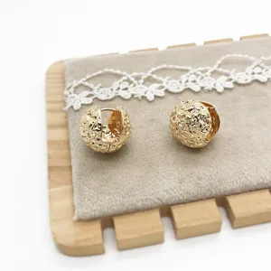 Detailed view of textured gold-colored circular earrings with a molten hammered finish.