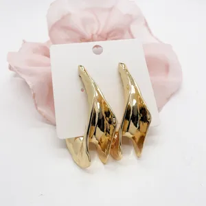 Detailed view of exaggerated chunky gold geometric earrings with high-shine metallic finish