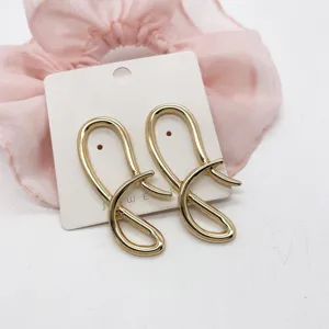 Close-up of gold-plated geometric abstract wavy stud earrings on a display card