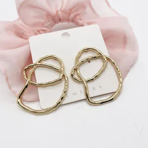 Close-up detail of gold irregular geometric alloy stud earrings with shiny finish