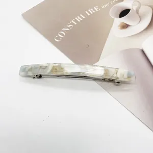 Close-up detail of a rectangular resin hair barrette with elegant white marble pattern