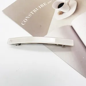 Macro view of a minimalist cream resin rectangular hair clip showing its smooth texture