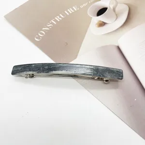 Detail view of a rectangular gray marble resin hair clip on a minimalist background