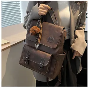 Vista dettagliata dello zaino vintage in pelle PU marrone con portachiavi a orsetto.