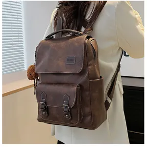 Dettaglio di zaino vintage in pelle PU marrone con portachiavi a orso indossato da modella.