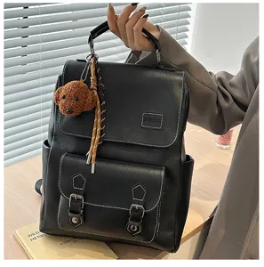 Dettaglio zaino vintage in pelle PU nera con grazioso ciondolo a forma di cane.