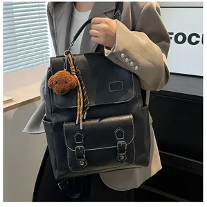 Dettaglio di uno zaino vintage in pelle PU nera con ciondolo a forma di orsetto