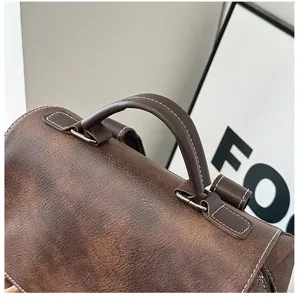Dettaglio del manico dello zaino vintage in pelle PU marrone con cuciture a contrasto.