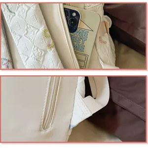 Detalle de cerca de mochila acolchada blanca que muestra bolsillo con cremallera y asa.