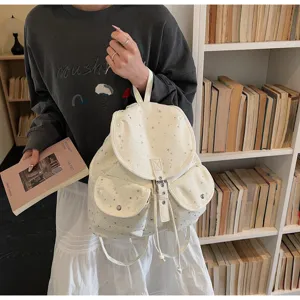 Minimalist campus style off-white backpack with silver star patterns in a library