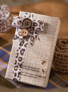Detalle de cinta decorativa de leopardo y botones de madera sobre una caja de regalo