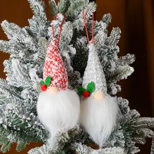 Dettaglio di ornamenti per gnomi di Natale in maglia su rami di pino innevati