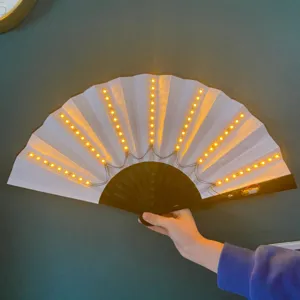 Nahaufnahme eines weißen 10-Zoll-LED-Faltfächers mit warmen gelben Lichtern an der Wand