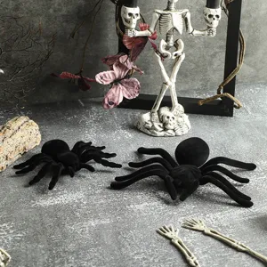 Detailed shot of black flocked Halloween spider decoration props on textured grey tabletop.