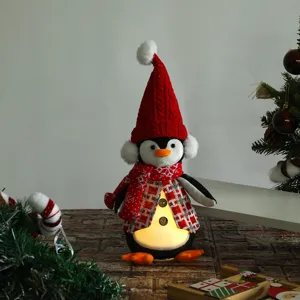 Primo piano di un pinguino di Natale di peluche con luce LED e cappello rosso
