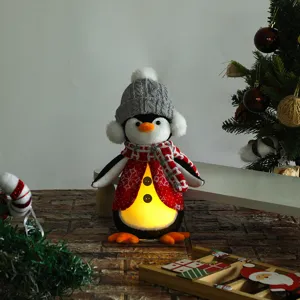 Dettaglio ravvicinato di un pinguino natalizio in peluche con pancia luminosa LED
