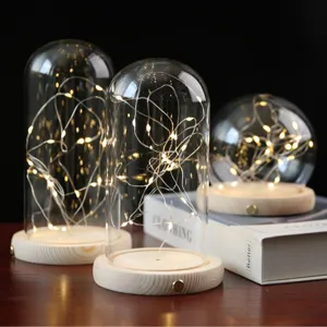 Lampe globe en verre LED avec socle en bois et guirlande lumineuse en fil de cuivre.