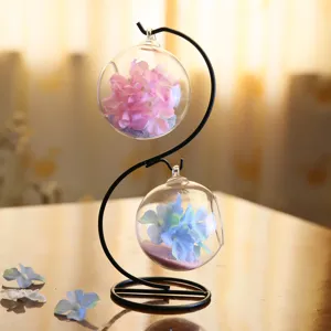 Supporto in ferro a S con due globi di vetro sospesi, ideale per decorazioni da tavolo.
