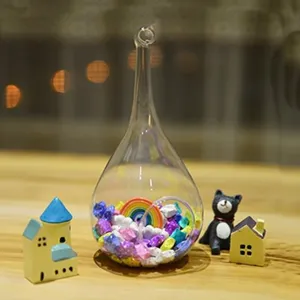 Glass terrarium vase detail view, clear teardrop hanging bottle with miniature landscape decor.