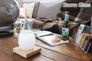 Detailed shot of a clear glass teardrop storm glass weather forecaster on wooden base.