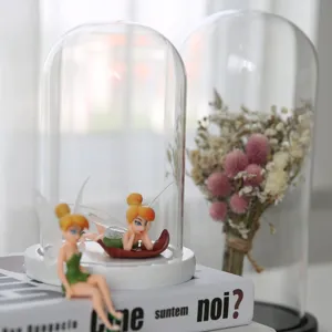 Large clear glass dome with fairy figurine ornament and preserved flower display decor.