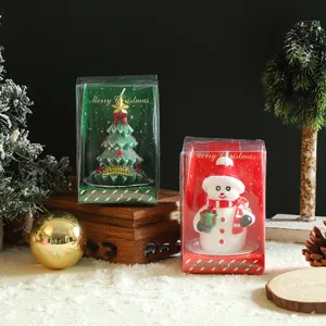 Christmas tree and snowman shape scented candles in clear display boxes, festive desktop gifts.
