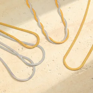 Macro view of gold and silver herringbone snake chain necklaces on stone surface