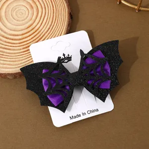 Detail view of Halloween bat wing hair clip with purple ribbon and black glitter spiderweb.