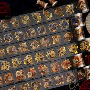Macro detail of dark floral PET tape rolls featuring iridescent gold foil for scrapbooking