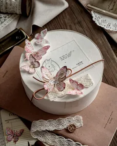 Primer plano de pegatinas de mariposas vintage y encaje decorando una caja de regalo blanca