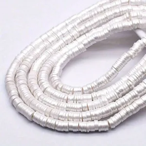 Détail macro de perles Heishi plates en argile polymère blanche de 6 mm pour bijoux.