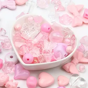 Close-up of mixed pink acrylic beads in a heart bowl for DIY jewelry and phone charms.