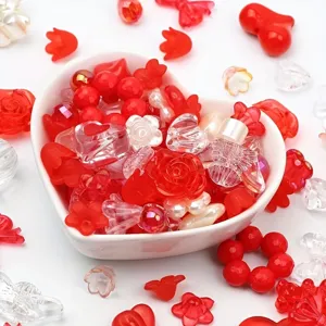 Detail shot of various red and clear acrylic mixed beads inside a heart-shaped ceramic bowl