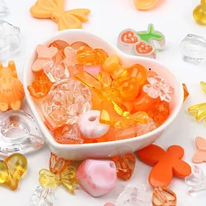 Close-up of colorful mixed shape acrylic beads and charms in a heart-shaped bowl
