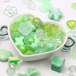 Close-up of assorted green acrylic beads for DIY jewelry and crafts in a bowl