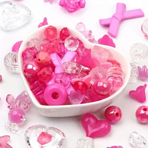 Macro view of mixed pink acrylic beads in heart-shaped bowl for DIY jewelry making
