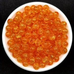Macro view of 8mm orange crackle acrylic beads inside a white bowl for DIY jewelry